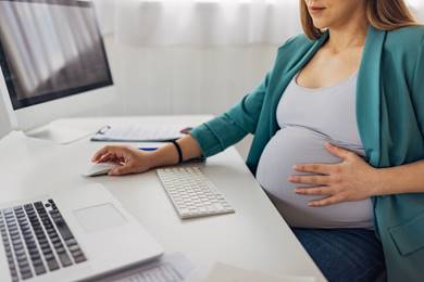Pregnant woman holding belly at work - Pregnancy Discrimination